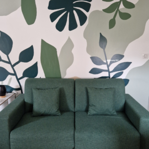 Image d'un canapé vert convertible devant sa fresque jungle DIY.