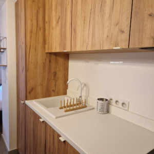 Image d'une cuisine en bois et son plan de travail blanc, équipée et aménagée.