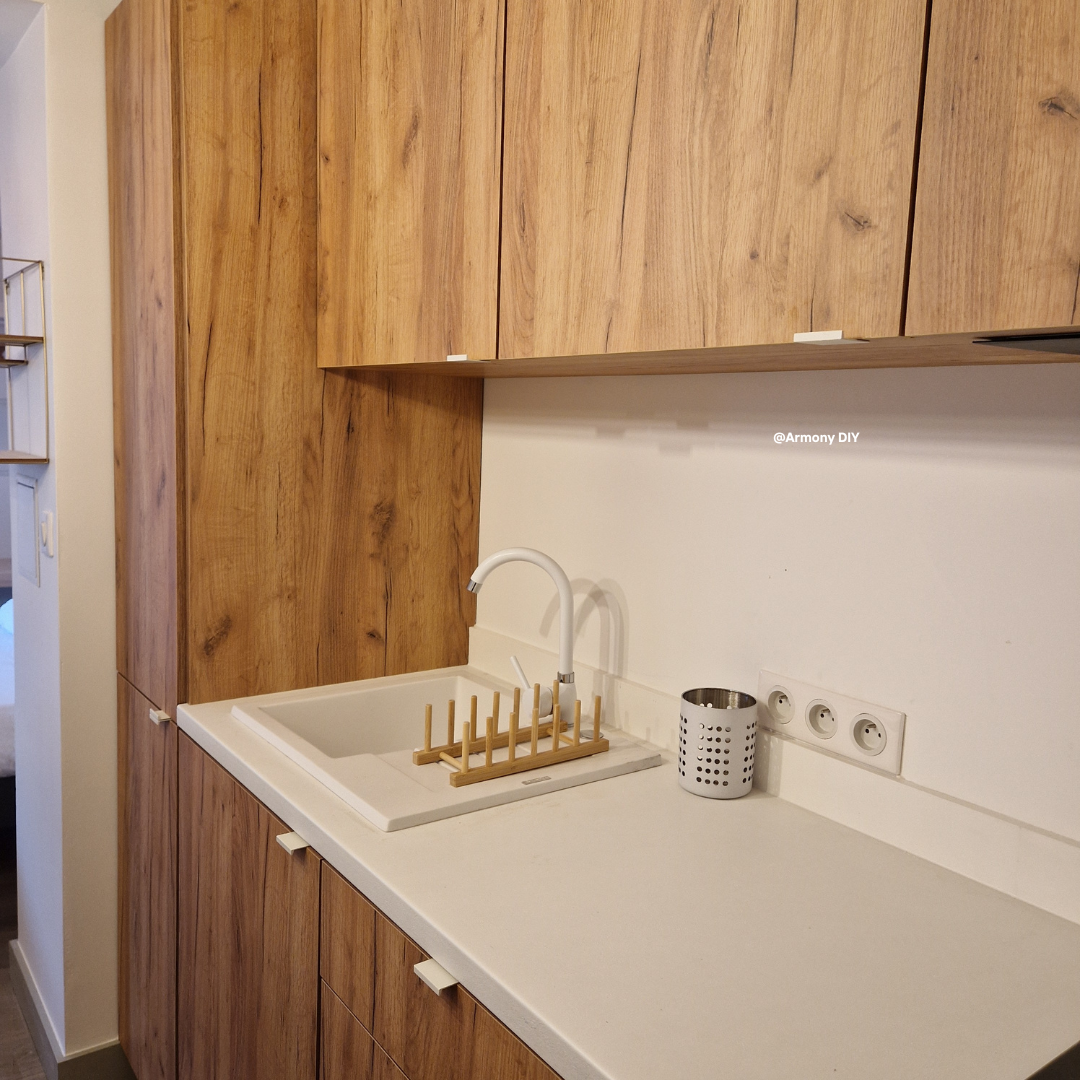 Image d'une cuisine en bois et son plan de travail blanc, équipée et aménagée.